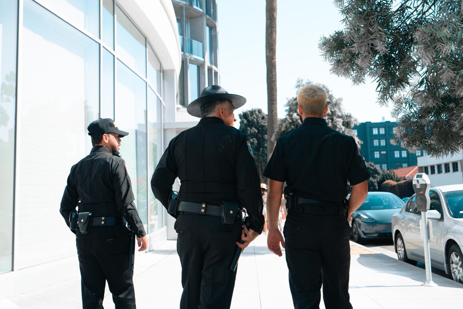 Three police officers standing on a sidewalk near a building.