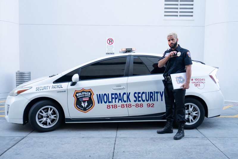 A security guard standing next to a car.