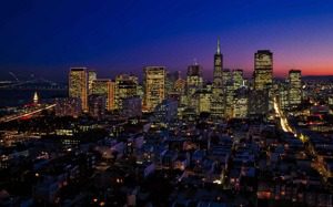 A city skyline with buildings lit up at night.