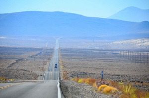 A road with cars driving down it in the middle of nowhere.