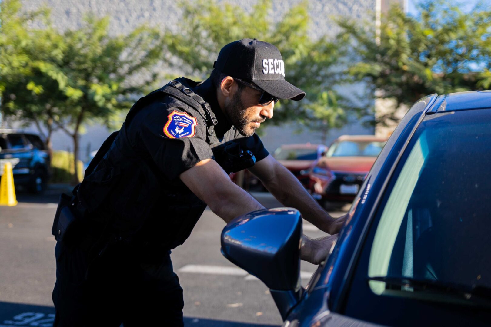 A police officer is looking into the side mirror of his car.
